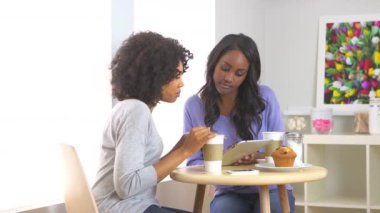 Afro-Amerikalı arkadaşlar kafede tablet kullanıyorlar.