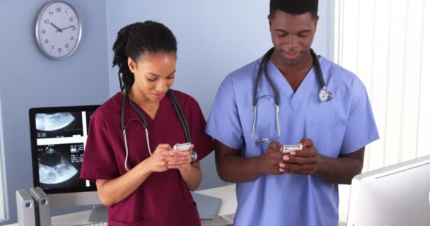 非裔美国人医疗同事一边笑一边用手机 — 图库视频影像