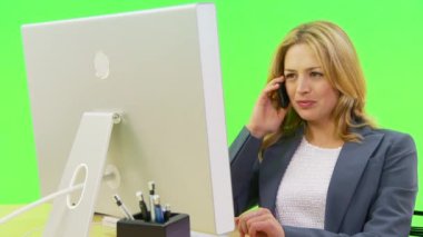 İş kadını bilgisayar kullanırken telefonla konuşuyor