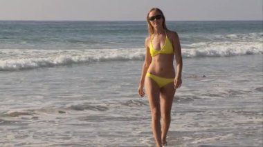 Plajda sarı benekli bikinili genç bir kadın.