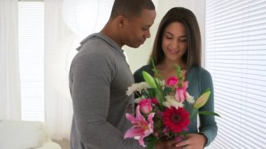 Siyah bir adam kız arkadaşına çiçek veriyor ve öpüşüyor.