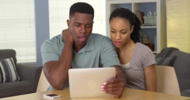 Afro-Amerikalı çift, doktorla tablet bilgisayarda boyun ağrısı hakkında konuşuyor.