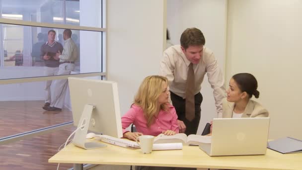 バックグラウンドで同僚と机の上にいるビジネスマン — ストック動画