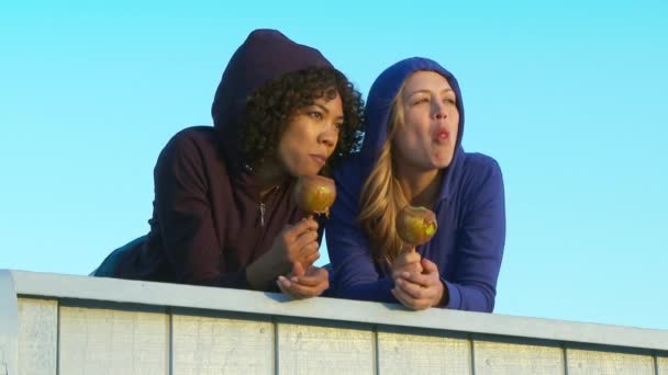 两个女性朋友在海滩边吃糖果苹果 — 图库视频影像