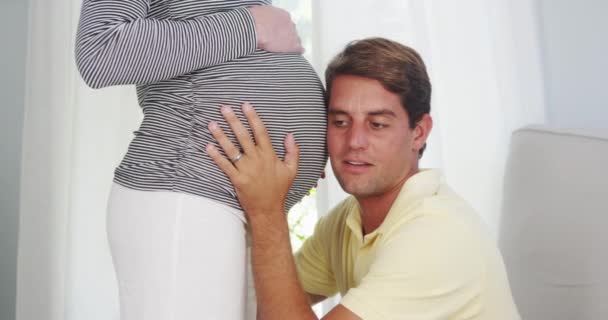 興奮したお父さんキス妊娠中の女性の腹 — ストック動画