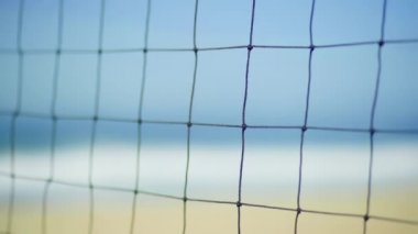 Plajda voleybol kalesine yakın durun. Spor ağlarından deniz dalgalarının görüntüsü. 4k