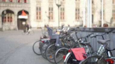 Avrupa şehir meydanındaki bisiklet parkında kompozitonun odak alanı dışında. Bruges 'de park etmiş bisikletlerin bulanık video arka planı. 4k