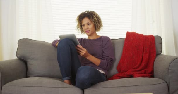 Szczęśliwy Czarna Kobieta Siedzi Kanapie Przy Użyciu Tabletu — Wideo stockowe