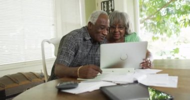 Mutlu kıdemli Afrikalı çift laptoptaki faturaları ödüyor.