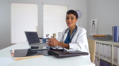 Masadaki doktor kamerayla konuşuyor.