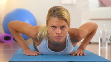 Şınav çeken ve kameraya bakan sağlıklı bir kadın.