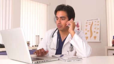 Cep telefonu üzerinde konuşurken ve dizüstü bilgisayar kullanarak İspanyol doktor