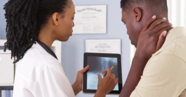 Hastanın boyun ağrısı için kadın doktor röntgen hakkında tablete konuşuyor.