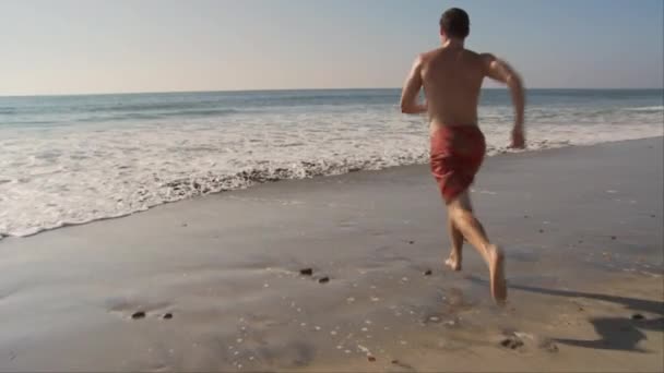 Joven Corriendo Hacia Las Olas Del Océano Playa — Vídeos de Stock