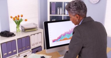 Ayakta ve bilgisayarda çalışan siyah işkadını