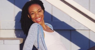 Açık merdivenler gülüyor üzerinde oturan mutlu siyah kadın