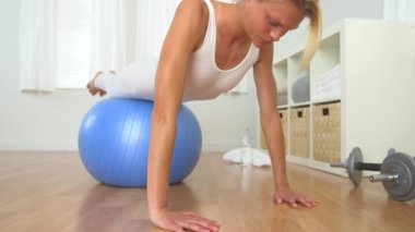 Sağlıklı sarışın kadın denge topuyla şınav çekiyor.