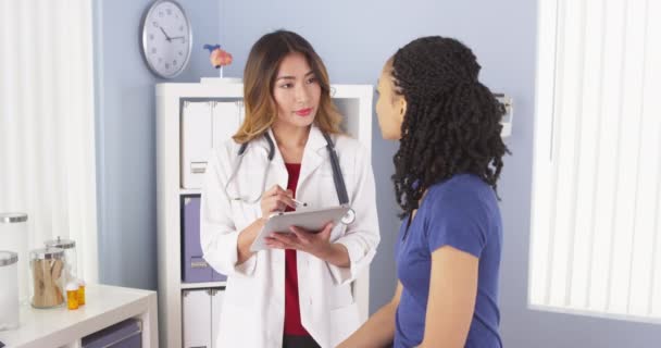 Japanese Doctor Taking Notes Talking African American Patient — Stock Video