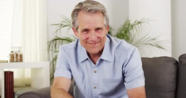 Kanepede gülümseyen yakışıklı olgun adam.