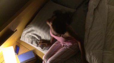 Genç kadın uyumak için yatağa giriyor.