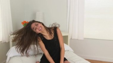 Genç beyaz kadın yatakta dans ediyor.