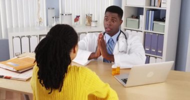 Ofis masasında siyahi bir kadın samimi bir Afrikalı Amerikalı doktorla konuşuyor.