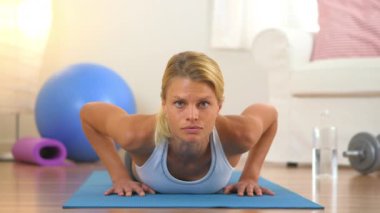 Şınav çeken ve kameraya bakan sağlıklı bir kadın.