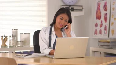 Japon doktor ofiste telefonla konuşuyor.