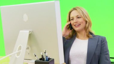 İş kadını bilgisayar kullanırken telefonla konuşuyor