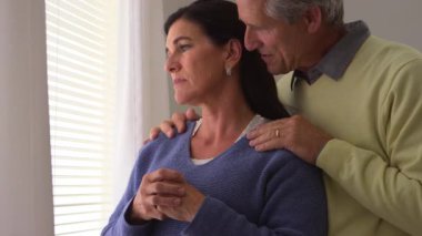 Yaşlı kadın kocasıyla pencerenin önünde yas tutuyor.