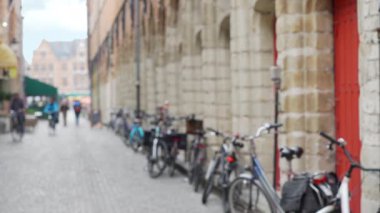 Avrupa şehrinde park halindeki bisikletlerle dolu bir arka plan plakası. Bruges 'deki kaldırım taşı caddesindeki bulanık insanların ve bisikletlerin video arkaplanı. 4k