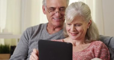 Kanepede tablet kullanan güzel yaşlı çift.