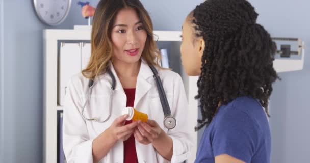 黒人の患者に新しい処方を説明するアジアの医師 — ストック動画