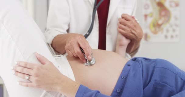 Starszym Lekarzem Słuchanie Kobieta Ciąży Brzuch — Wideo stockowe
