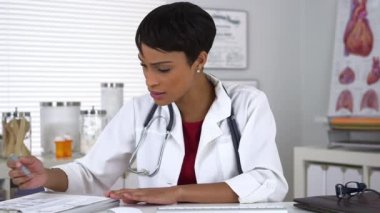 Siyahi doktor kameraya konuşuyor ve not alıyor.