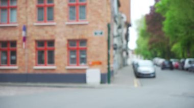 Sağda ağaçlar, solda tuğla binalar olan işlek şehir caddesinin arka plan plakasının dışında. Yayalar, bisikletler ve arabalarla birleştirilmiş yeşil ekran için video arkaplanı. 4k