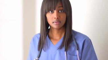 Siyah kadın doktor kameraya bakıyor.