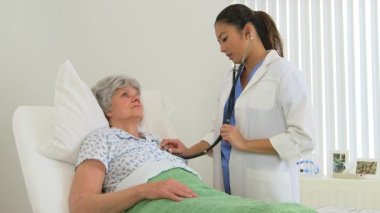 Kadın çok ırklı doktor hastasının kalp atışlarını dinliyor.