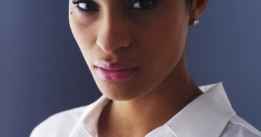 Ciddi bir kadın ayakta kameraya bakıyor.