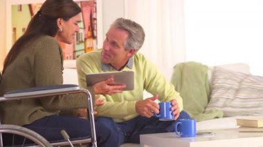 Yaşlı çift tabletteki eski fotoğraflara bakıyor.