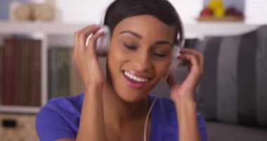 Zenci kadın kulaklıkla müzik dinliyor.