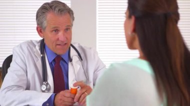 Doktor kadın hastaya ilaç yazıyor.