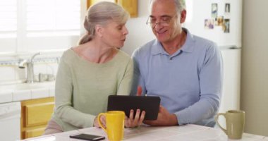 Mutfakta tablet kullanan mutlu yaşlı çift.