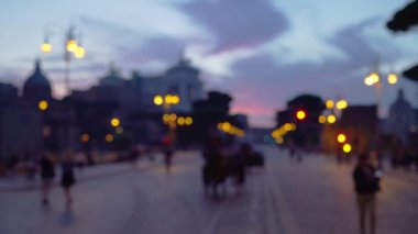 Roma 'da, İtalya Ulusal Victor Emmanuel Anıtı' nın yakınındaki kentsel ortamda odaklanmış gece sahnesi. Bokeh 'te, İtalya' da turistlerin şehir simgesi yakınlarındaki caddelerde yürüdüğü gece çekimleri