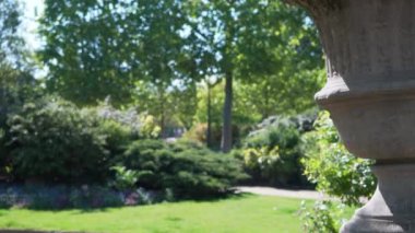 Avrupa parkındaki beton heykel vazosuna yakından bak. Arkaplanda yemyeşil bir park ve Paris 'te büyük bir taş heykel var.