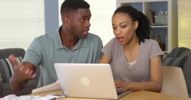 Genç siyah çift faturaları ve mali dizüstü bilgisayar ile savunarak üzgün