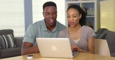 Mutlu genç siyah çift gülüyor ve laptop komik video izlerken