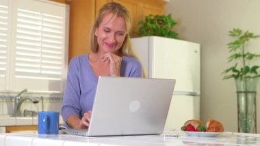 Kahve içen ve laptop kullanan olgun bir kadın.