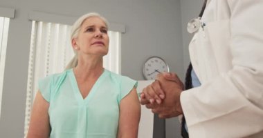 Genç siyah erkek doktor yaşlı kadın hastayla gelecekteki sağlığını tartışıyor. Doktorların tıbbi tavsiyelerini dinleyen Kafkas kadınlarına yakın durun.