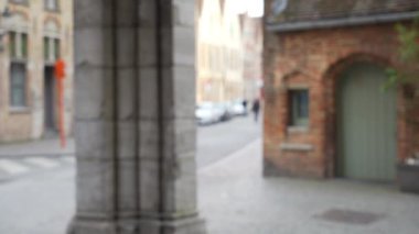 Avrupa şehir caddesinin odak alanı dışında, ön planda birleşim için geniş bir sütun var. Bulanık insanların sokakta yürüdüğü bir video. 4k